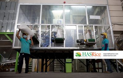 Workers loading sacks into the intake hopper on the milling platform